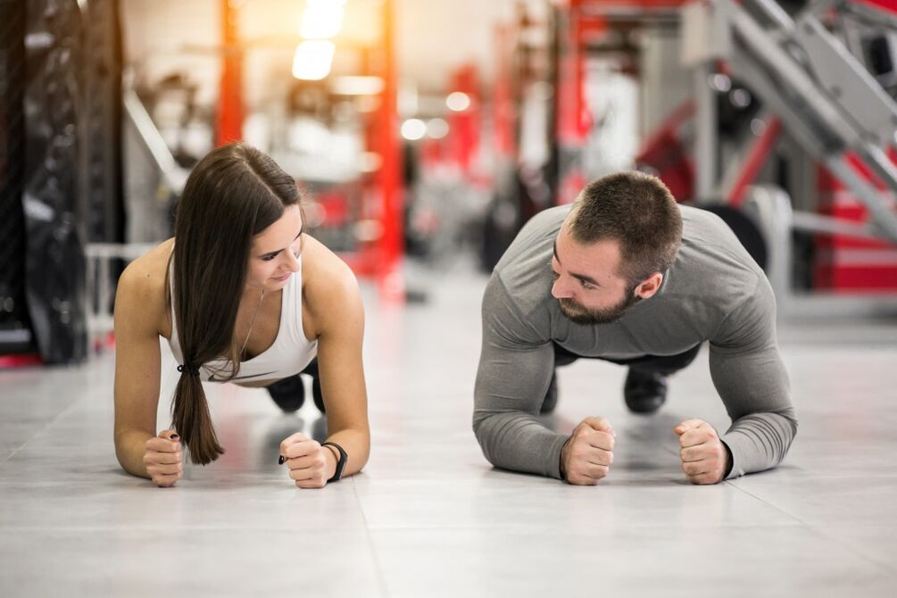 Un hombre y una mujer realizan el ejercicio de plancha diseñado para todos los grupos musculares